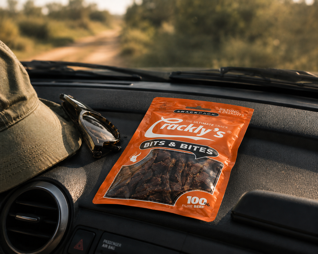 Cracklys Bits & Bites snack pack on a bakkie dashboard, SA dirt road in the background